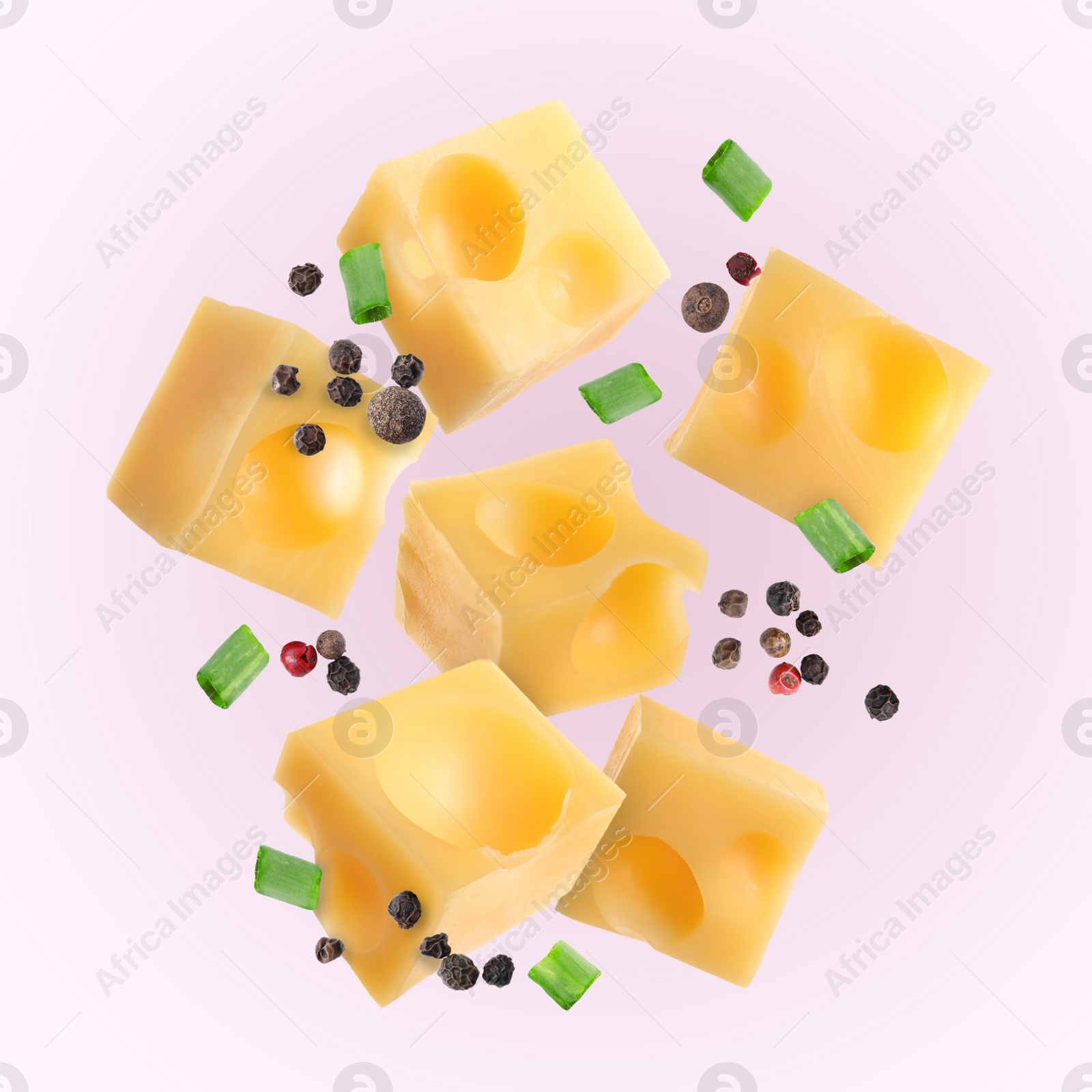 Image of Pieces of tasty cheese, green onion and spices falling on light pink background