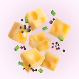 Image of Pieces of tasty cheese, green onion and spices falling on light pink background