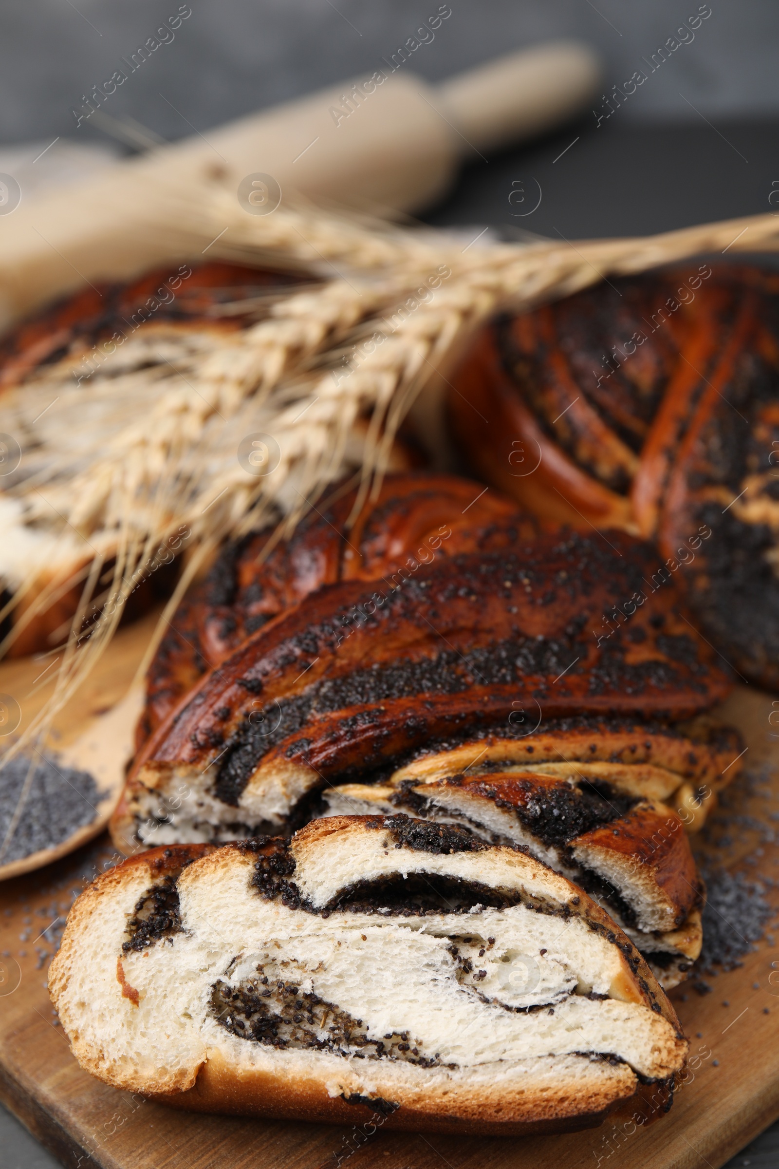 Photo of Pieces of poppy seed roll on wooden board, closeup with space for text. Tasty cake