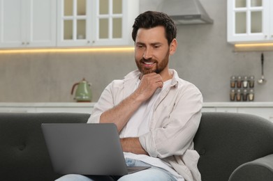 Man using laptop on couch at home