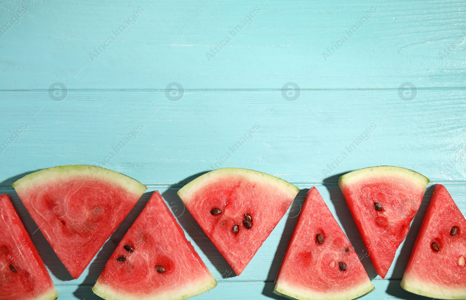 Photo of Slices of ripe watermelon on light blue wooden table, flat lay. Space for text