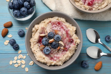 Photo of Tasty oatmeal porridge with toppings served on light blue wooden table, flat lay