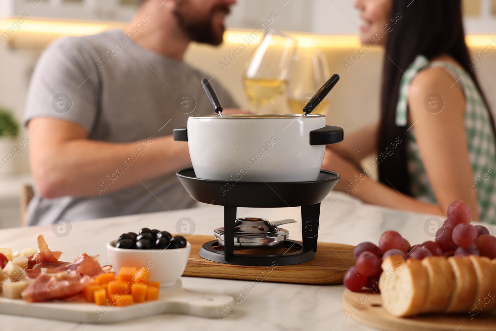 Photo of Couple spending time together during romantic date in kitchen, focus on fondue