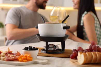 Photo of Couple spending time together during romantic date in kitchen, focus on fondue