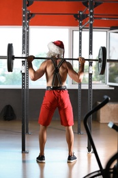 Photo of Young muscular man in Santa costume training at gym