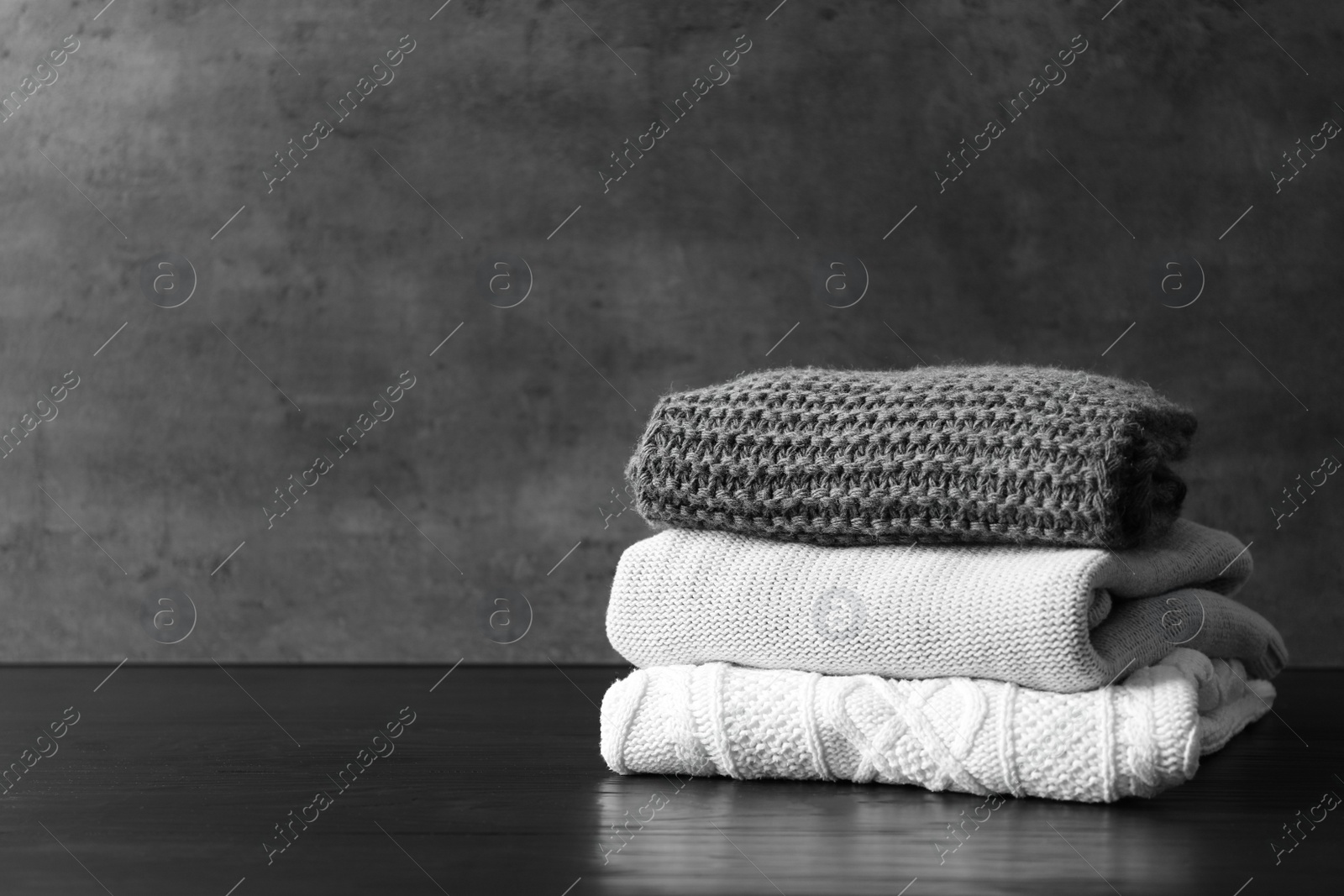 Photo of Stack of warm knitted clothes on table