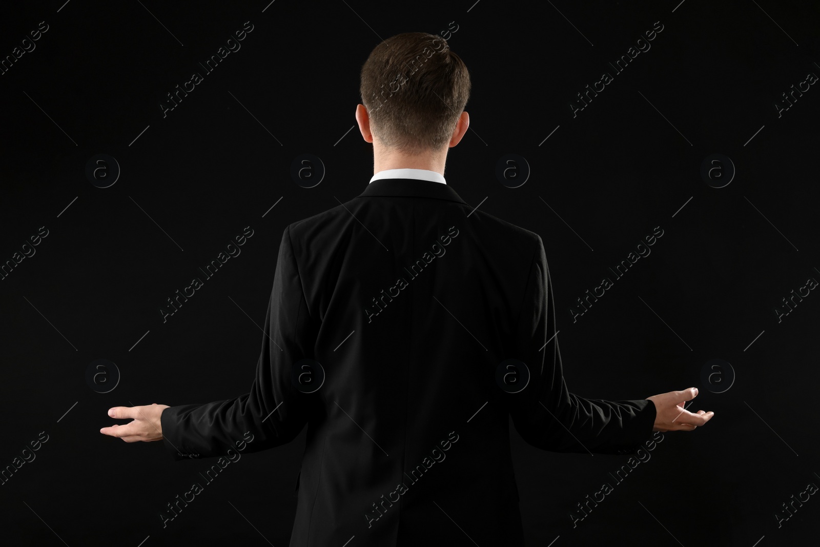 Photo of Man in suit on black background, back view