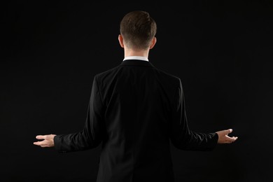 Man in suit on black background, back view