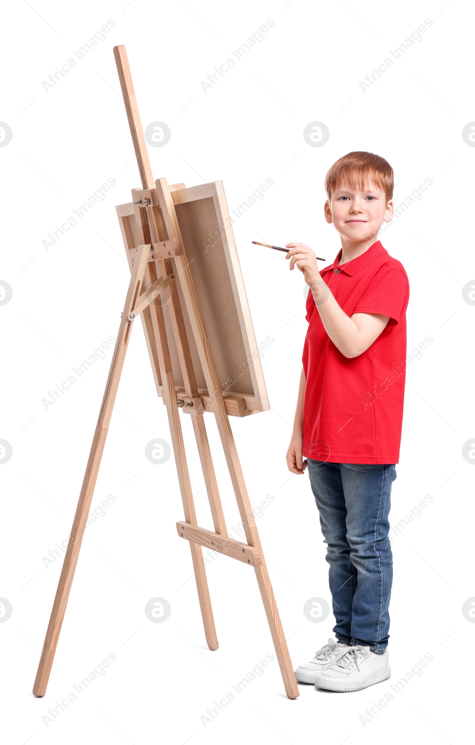 Photo of Little boy painting against white background. Using easel to hold canvas