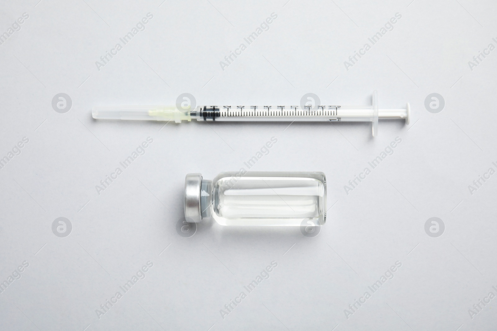 Photo of Vial and syringe on light background, flat lay. Vaccination and immunization