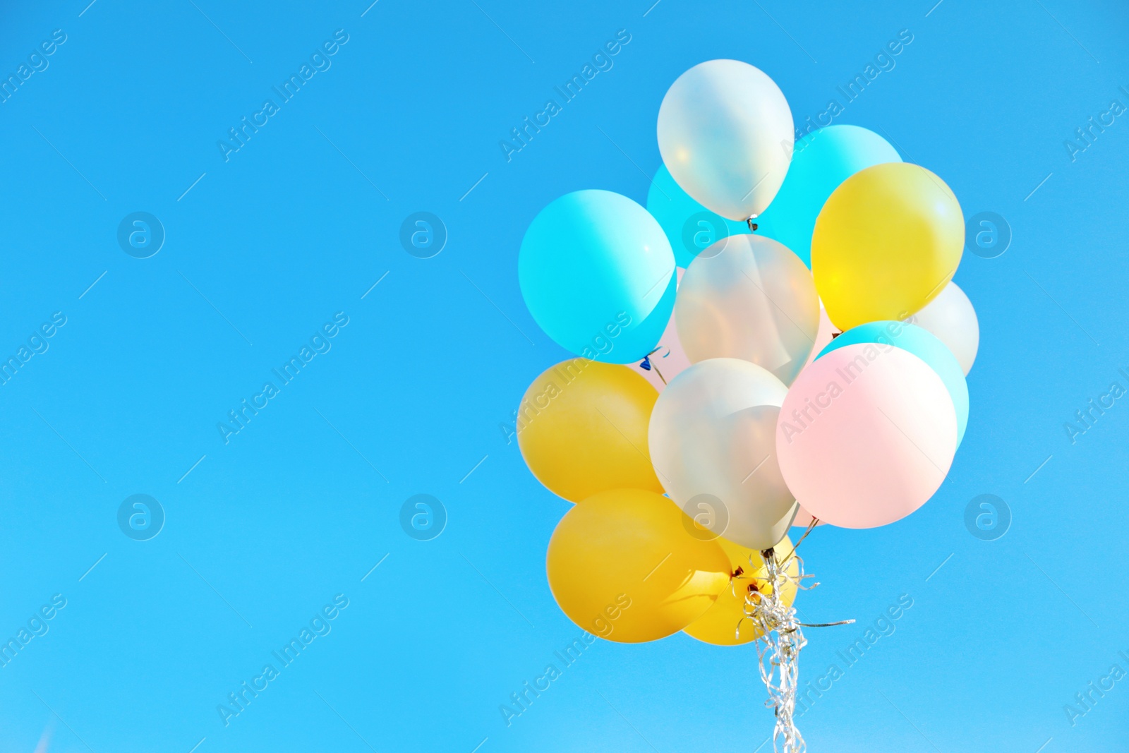 Photo of Bunch of colorful balloons against clear blue sky on sunny day. Space for text
