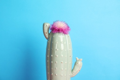 Trendy cactus shaped ceramic vase with flower on color background