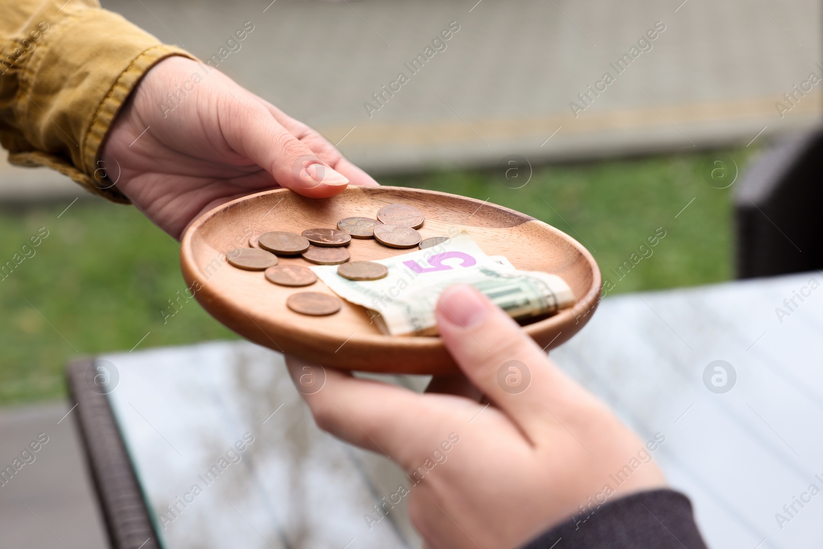 Photo of Client giving tips to waitress in outdoor cafe, closeup