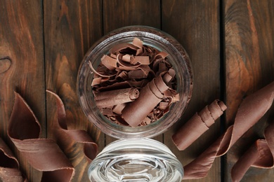 Flat lay composition with jar of chocolate curls on wooden background