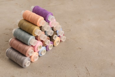 Photo of Set of color sewing threads on grey table, space for text