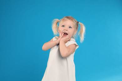 Cute little girl posing on light blue background