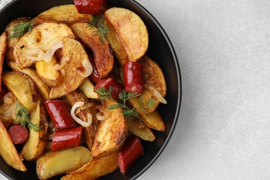 Photo of Delicious baked potato with thin dry smoked sausages, onion and dill in bowl on gray table, top view. Space for text