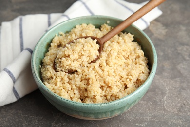 Photo of Composition with cooked quinoa in bowl and wooden spoon on table