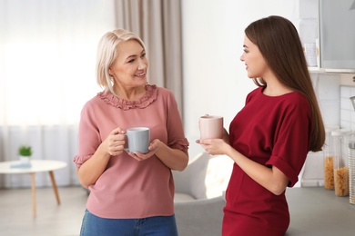 Photo of Portrait of mature woman and her daughter drinking tea in kitchen
