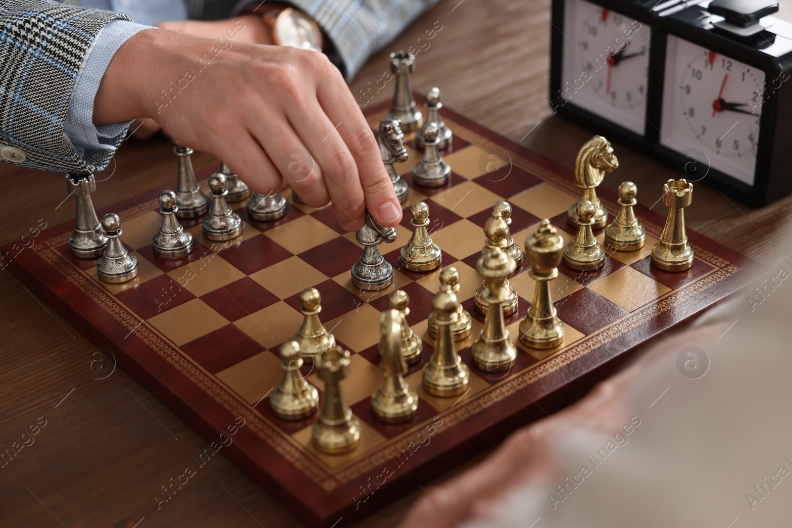 Photo of Men playing chess during tournament at wooden table, closeup