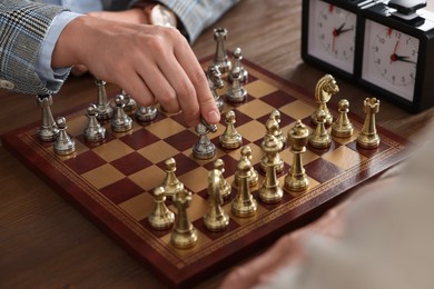 Photo of Men playing chess during tournament at wooden table, closeup