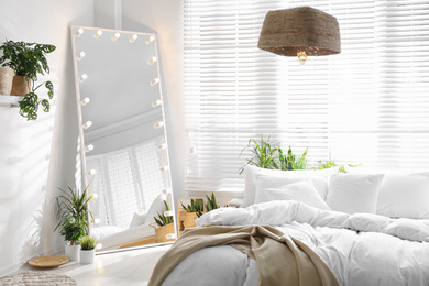 Photo of Stylish mirror with light bulbs in modern bedroom. Interior design