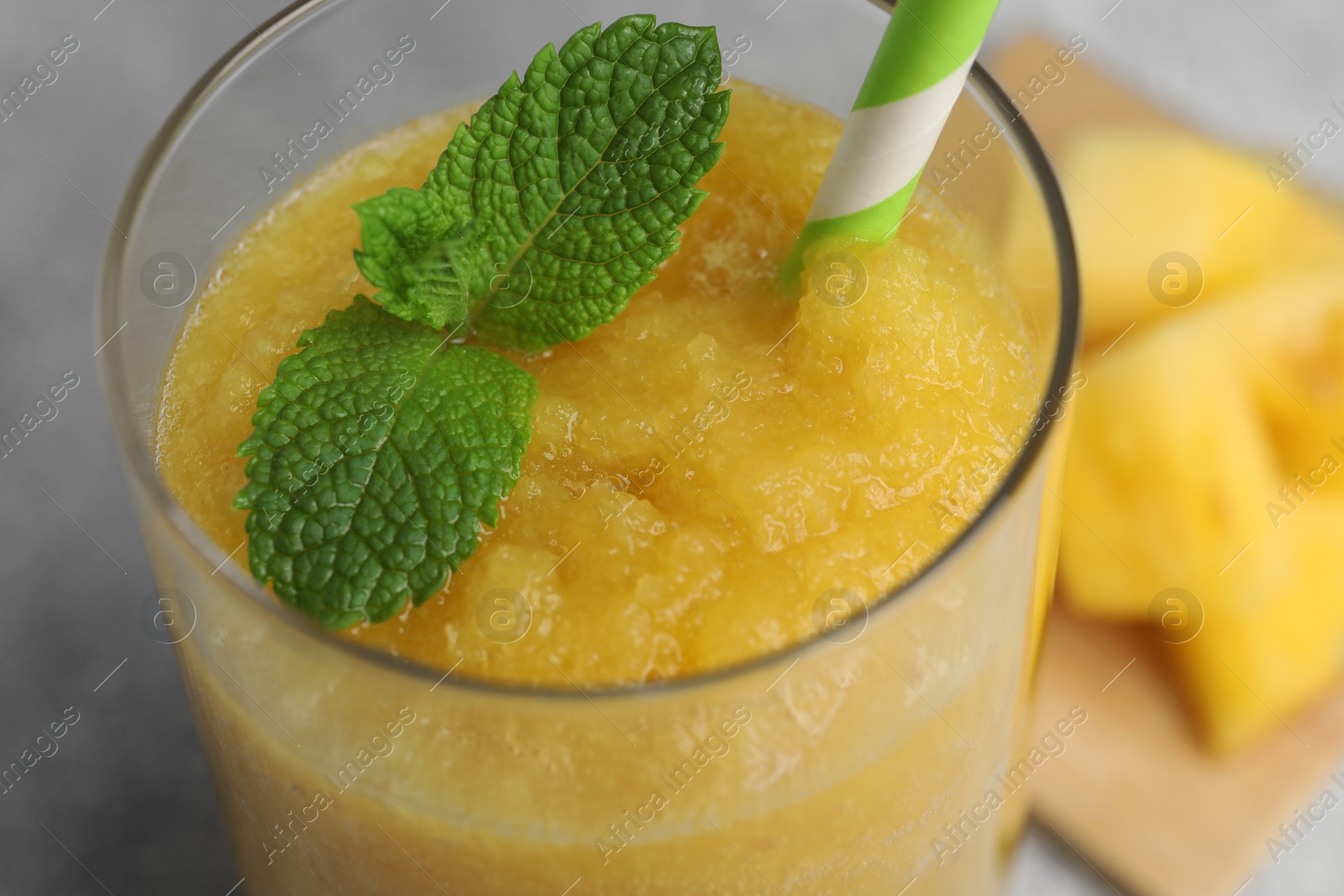 Photo of Glass of tasty pineapple smoothie with mint on light gray table, closeup
