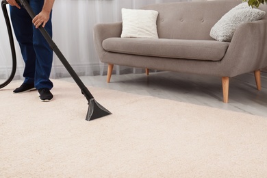 Photo of Man removing dirt from carpet with vacuum cleaner indoors, closeup. Space for text