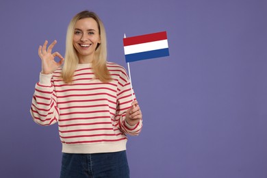 Image of Happy young woman with flag of France showing OK gesture on purple background