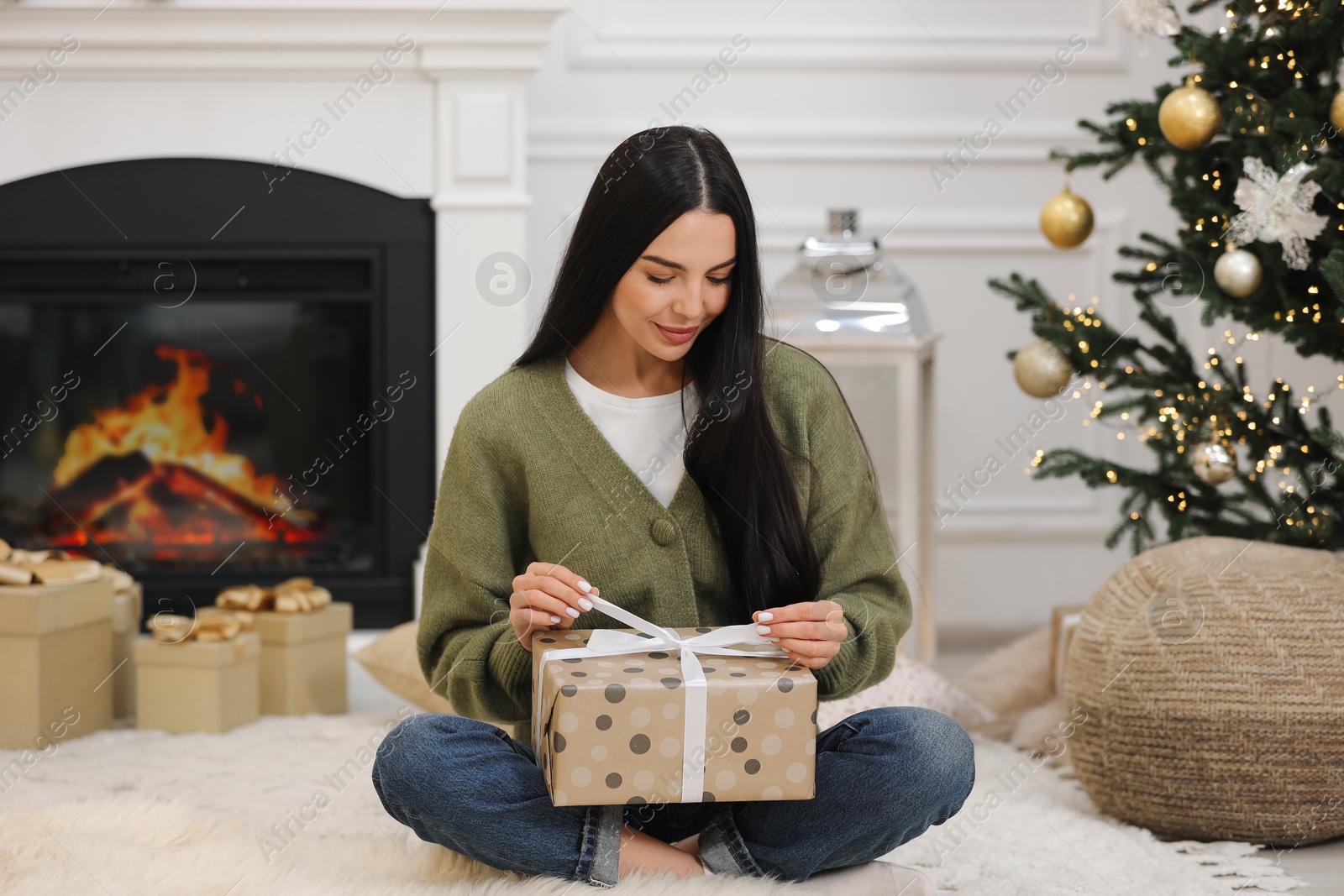 Photo of Beautiful woman opening Christmas gift at home