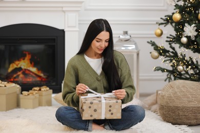 Photo of Beautiful woman opening Christmas gift at home