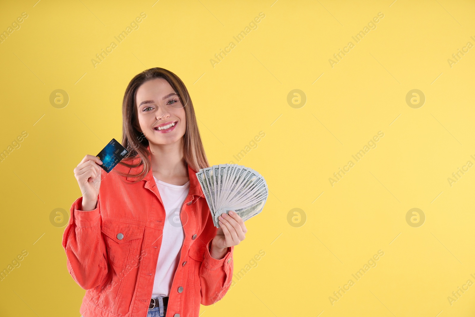 Photo of Young woman with money and credit card on yellow background. Space for text