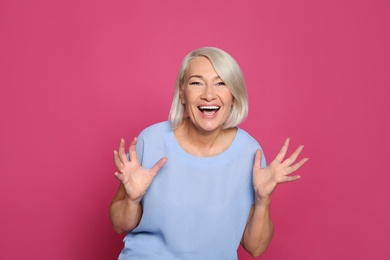 Photo of Portrait of mature woman laughing on color background