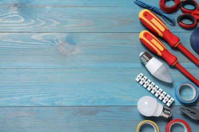 Photo of Set of electrician's tools and accessories on light blue wooden table, flat lay. Space for text