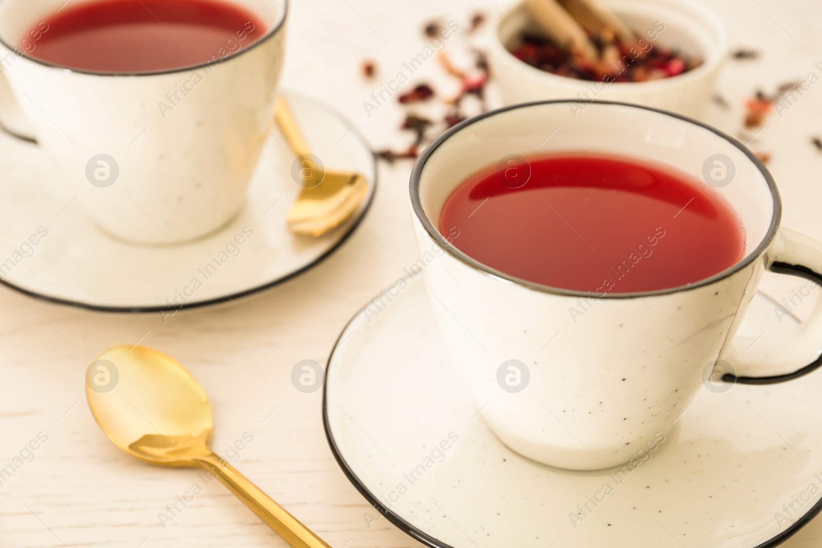 Photo of Cups of hibiscus tea on white wooden table