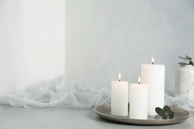 Photo of Burning candles on light grey stone table. Space for text