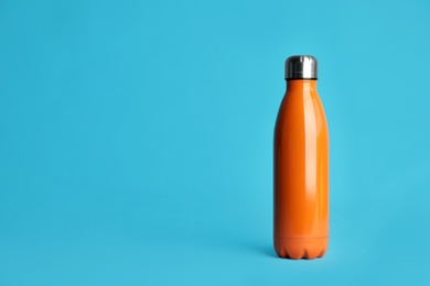 Photo of Stylish thermo bottle on light blue background, space for text