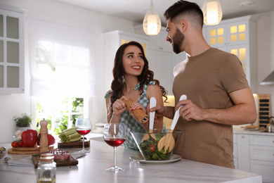 Photo of Lovely young couple cooking salad together in kitchen