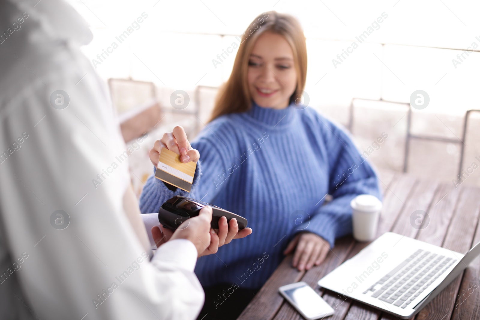 Photo of Woman with credit card using payment terminal at restaurant