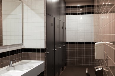 Public toilet interior with sinks, stalls and mirror