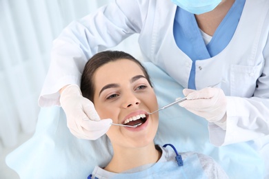 Photo of Dentist examining patient's teeth in modern clinic