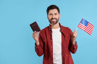 Photo of Immigration. Happy man with passport and American flag on light blue background, space for text