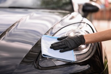 Woman wiping her modern car with rag, closeup