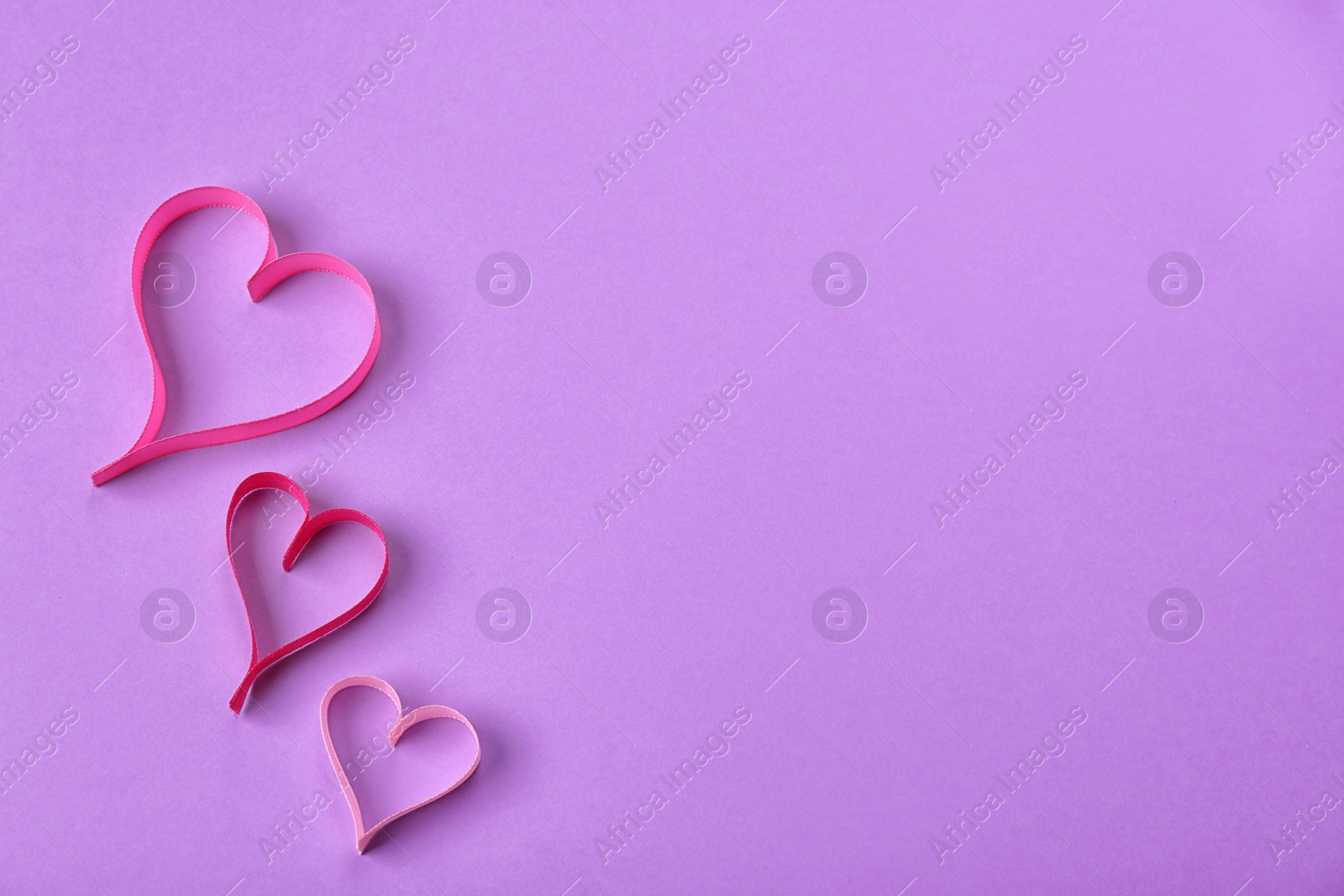 Photo of Hearts made of ribbons and space for text on color background, top view