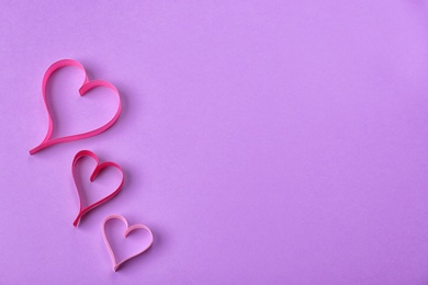 Hearts made of ribbons and space for text on color background, top view