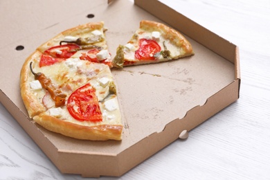 Cardboard box with tasty pizza slices on wooden table