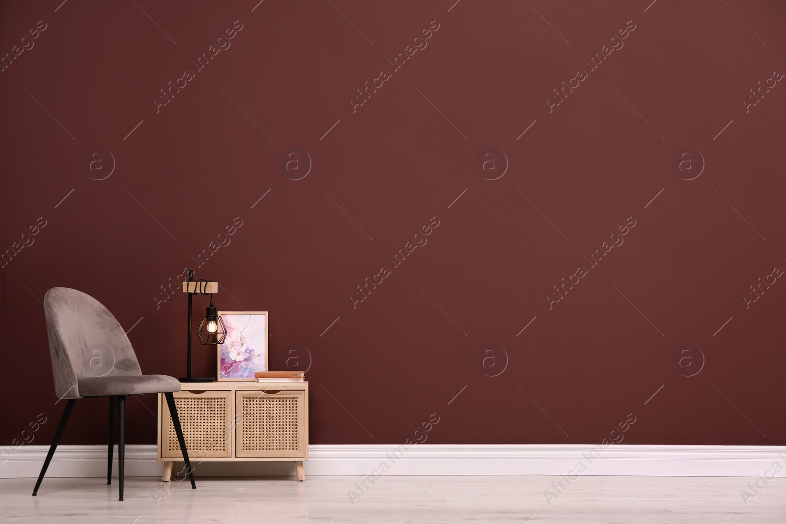 Photo of Stylish commode and armchair near brown wall, space for text