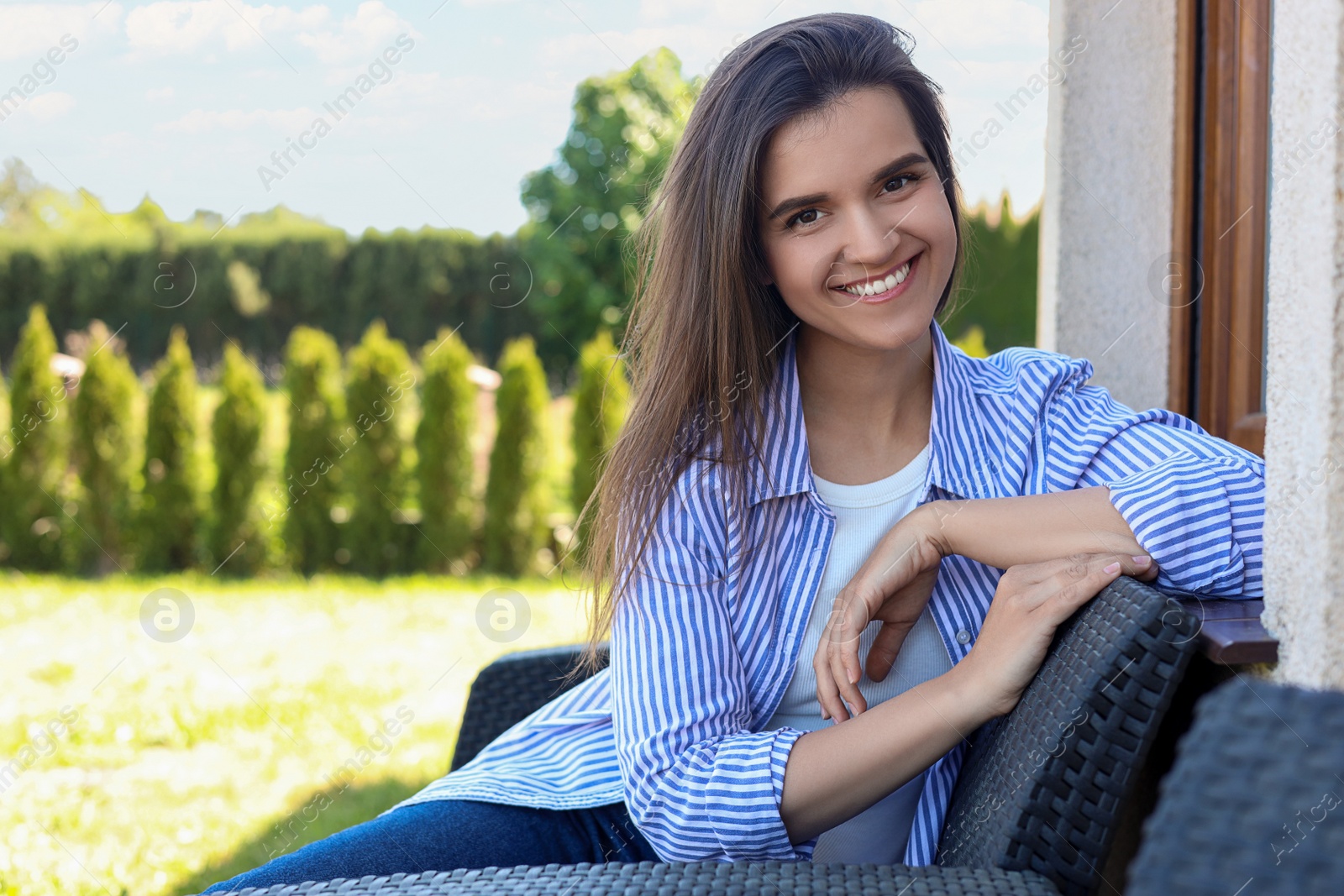 Photo of Portrait of beautiful young woman sitting on chair at backyard, space for text