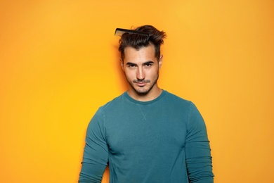 Photo of Young man with comb posing on color background. Trendy hairstyle