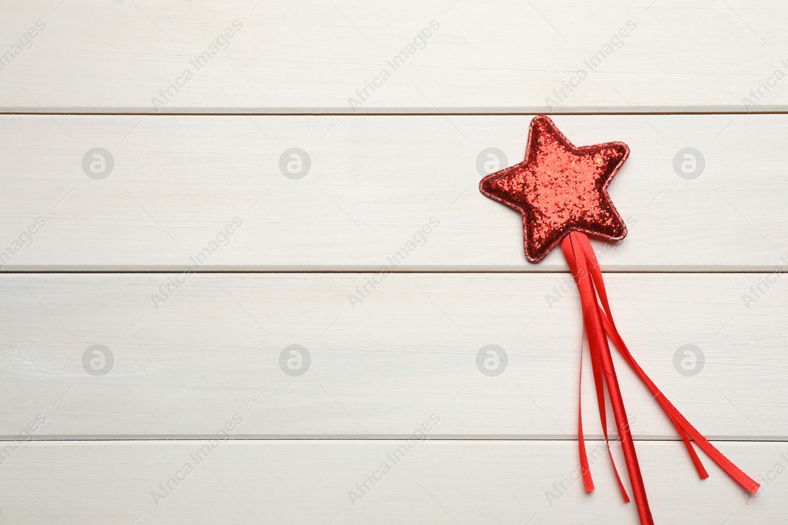 Photo of Beautiful red magic wand on white wooden table, top view. Space for text